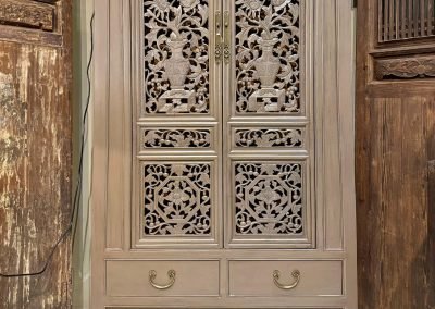 Tapered cabinet in taupe colour, with old carvings as doors