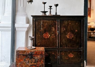 three antique Tibetan pieces: a cabinet with floral painting, a leather wrapped small box and a choksar