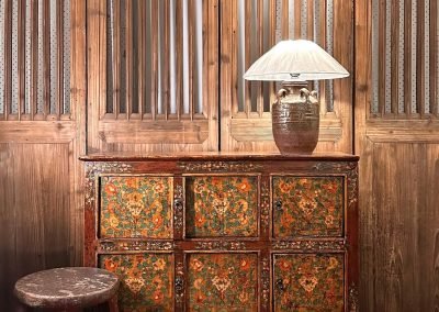 An antique painted tibetan cabinet in front of a set of tall antique chinese door panels